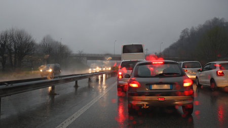Traffic jam in heavy rain on wet freeway with cars, vans and bus lights reflected in rain drops