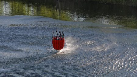 Detail of water bucket lifting out of the water under a helicopter with rotor wash on the surface of the lakeの写真素材