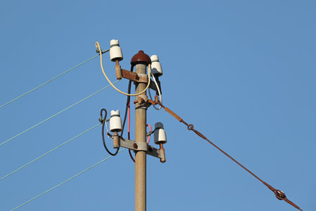 Powerlines at an electric metal pole against blue skies