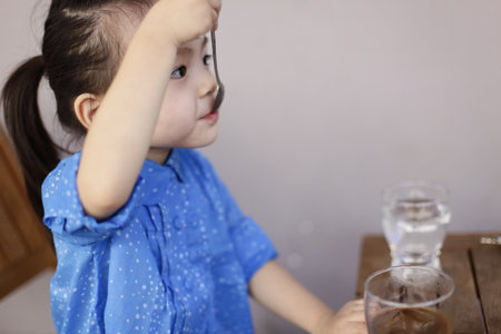 Cute lovely sweet asian chinese kid girl with smiling face on the road, jumping, running, and drink coffee.の写真素材