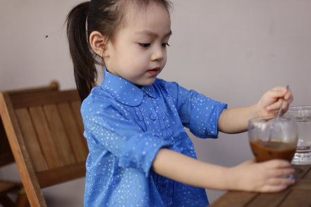 Cute lovely sweet asian chinese kid girl with smiling face on the road, jumping, running, and drink coffee.の写真素材