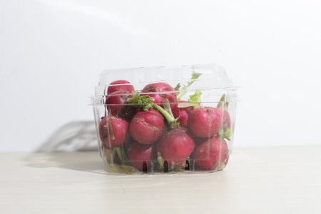 red radishes on wooden cutting board, with hand, knifeの写真素材