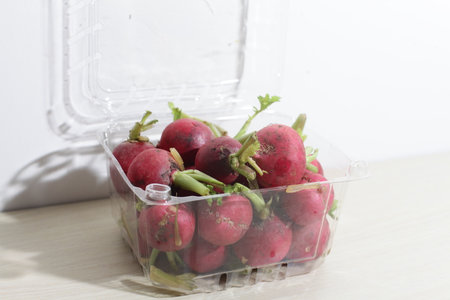 red radishes on wooden cutting board, with hand, knifeの写真素材