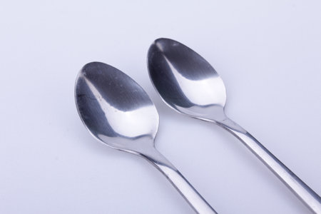 Silver spoon stands vertically with shadow isolated on white.の写真素材