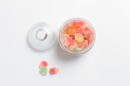 Colourful mashmallows in the glass bottle, on white background