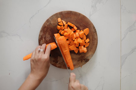 Woman cutting carrots on wooden board.の写真素材
