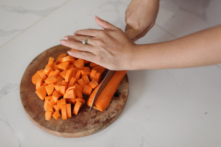 Woman cutting carrots on wooden board.の写真素材