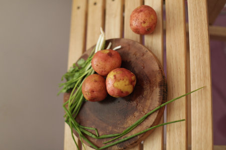 Sliced, peeled raw potatoes with a knife on a board, and scallionsの写真素材