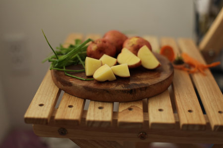 Sliced, peeled raw potatoes with a knife on a board, and scallionsの写真素材