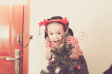 Cute baby girl decorate and play around the chirstmas tree.の写真素材