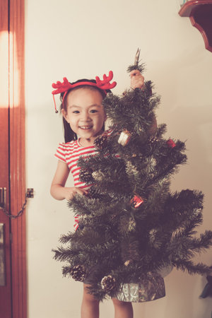 Cute baby girl decorate and play around the chirstmas tree.の写真素材