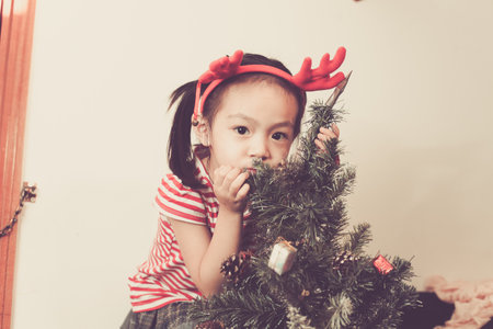 Cute baby girl decorate and play around the chirstmas tree.の写真素材