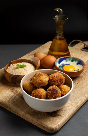 Homemade croquettes with their ingredients, dark rustic background with space for copy, striped...