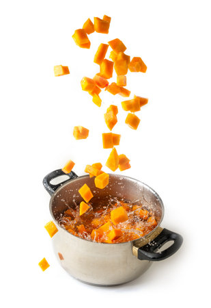 Diced pumpkin falling in a boiling pot, isolated white backgroundの写真素材