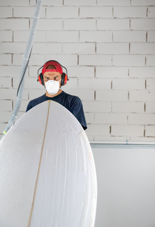Surfboard shaper workshop - man checking quality of surfboardの写真素材