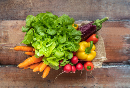 Fresh seasonal vegetables in a box on a wooden background - top viewの写真素材