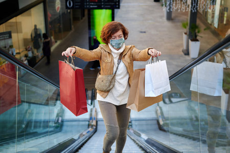 Happy woman shopping in a mall with face mask, new normal, covid-19の写真素材