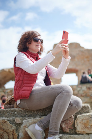 Middle-aged woman taking photo with her smart phone in outdoors with copy spaceの写真素材