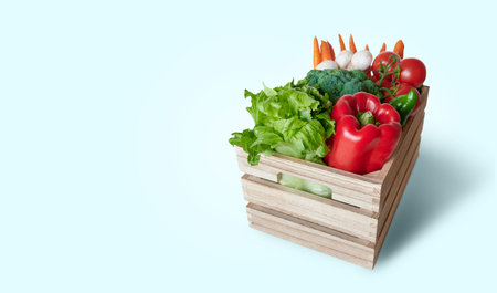 Fresh vegetables in insulated wooden box on blue background with space copyの写真素材
