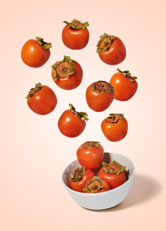 Fresh persimmons flying into a bowl isolated from the backgroundの写真素材