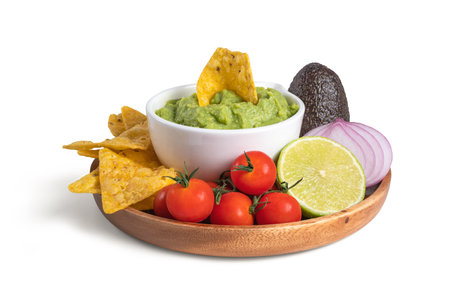 Guacamole bowl with nachos and ingredients, avocado, lime, onion, tomatoの写真素材