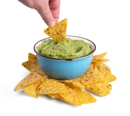 A hand dipping nachos in guacamole sauceの写真素材