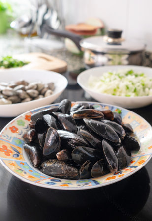 Fresh mussels are waiting to be cooked with chopped onions and clams in a home kitchen