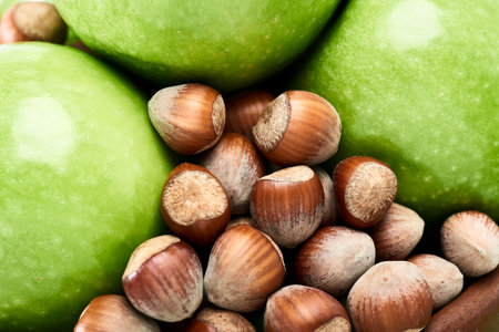 Brown hazelnuts and vibrant green of fresh Granny Smith apples close-up.の写真素材