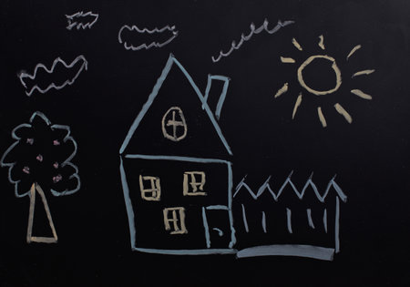 child's drawing with chalk on a blackboard, house, tree, sun.の写真素材