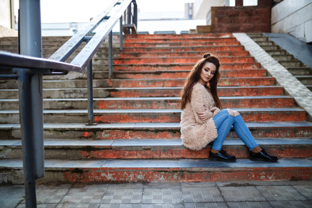 Beautiful young woman with long brown hair posing at the 	
outdoorsの写真素材