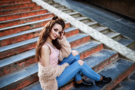 young beautiful happy girl in a coat posing at the streetの写真素材