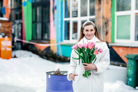 A young blonde woman with a bouquet of pink tulips in her handsの写真素材