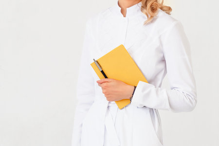 medical doctor writing down notes in a notebook isolated on white backgroundの写真素材
