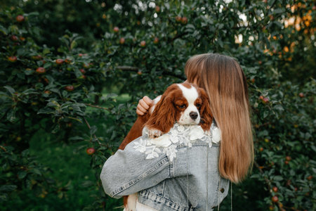 Close-up of young woman with her little dog, cocker spaniel breed puppy, outdoors, in a park.の写真素材