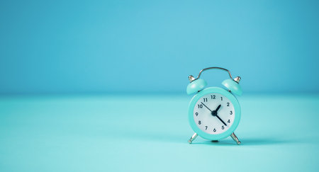 Blue small alarm clock on a blue background.