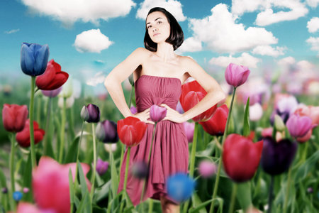 beauty young woman in red dress on the meadow with flowers tulipsの写真素材