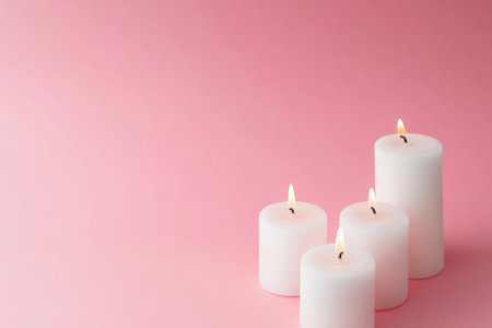 White candles flicker gently atop a soft pink backdrop, creating a calming atmosphere perfect for relaxation or peaceful moments.の素材