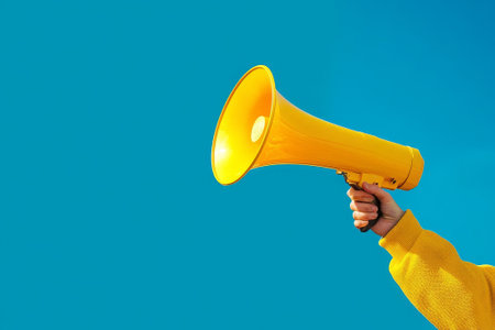 A person energetically holds a vivid yellow megaphone, set against a bold blue backdrop, emphasizing clarity and simplicity in design.の素材