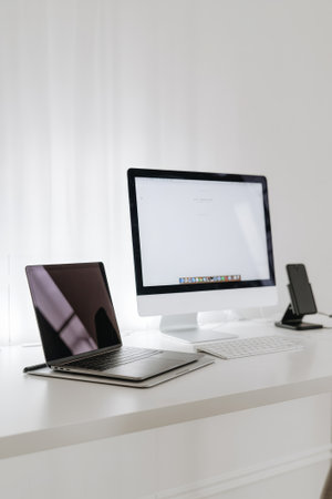 A minimalist workspace showcases a stylish desktop computer and a laptop on a clean, white surface, fostering inspiration and focus.の素材