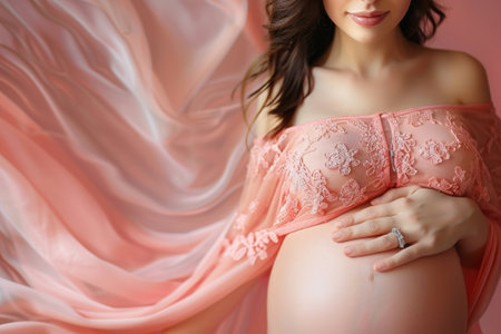 A glowing pregnant woman cradles her belly, draped in a soft, pink lace garment, showcasing the beauty of anticipation.の素材