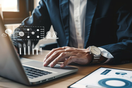 A businessman works on his laptop, analyzing sales performance data and charts. The image focuses on his hands and the laptop screen, showcasing a digital dashboard with graphs and metrics.の素材