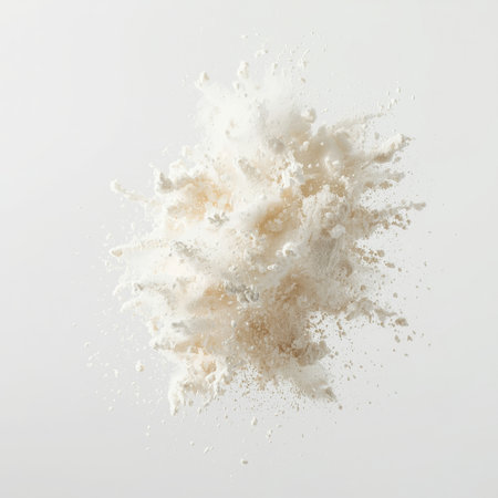 A burst of flour powder erupts against a clean white backdrop, showcasing the fine particles dispersing in the air. This striking visual captures the texture and movement in a moment of action.の素材