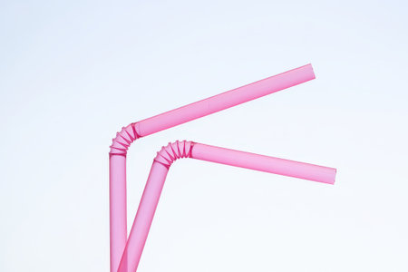 Two playful pink straws twisted in an artistic arrangement float against a bright, airy backdrop, evoking a sense of joy and whimsy.の素材