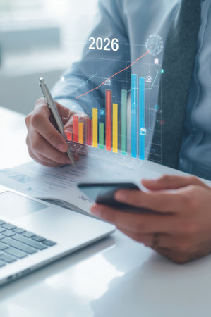 A business analytics professional analyzes data trends using a laptop and smartphone. Colorful graphs project future projections for 2026, showcasing a focus on growth and insights.の素材
