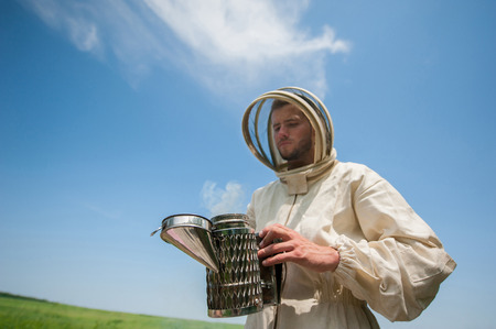 beekeeper with smoke tool. making clouds