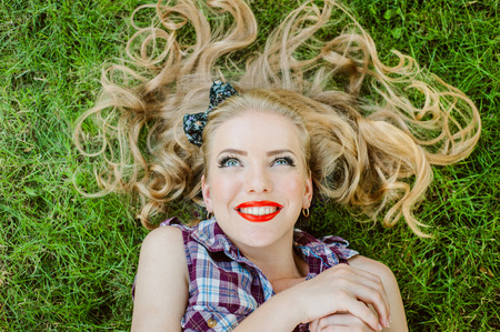Happy Girl blonde smiling lying on the grassの写真素材