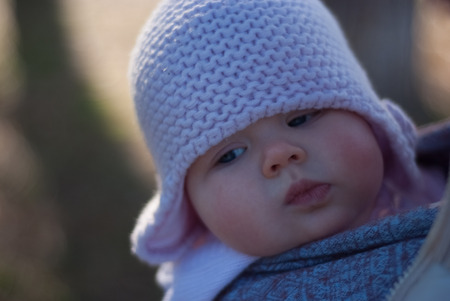 Baby in Knitted hat in a sling scarfの写真素材