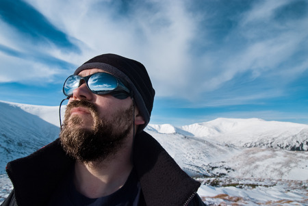 Portrait of a man with glasses and a beard in the snowy mountainsの写真素材