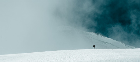 The man at the foot of a mountain peak in the clouds