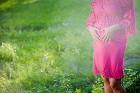 Beautiful tender pregnant woman stand on green meadow